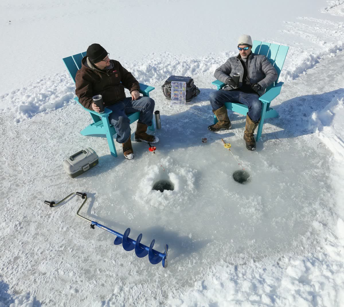 Two people ice fishing through holes in a frozen lake