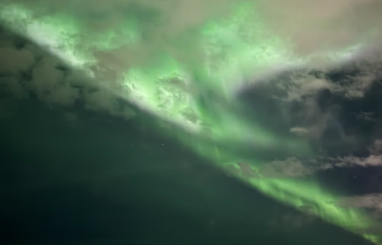 Bright green aurora shining through the clouds